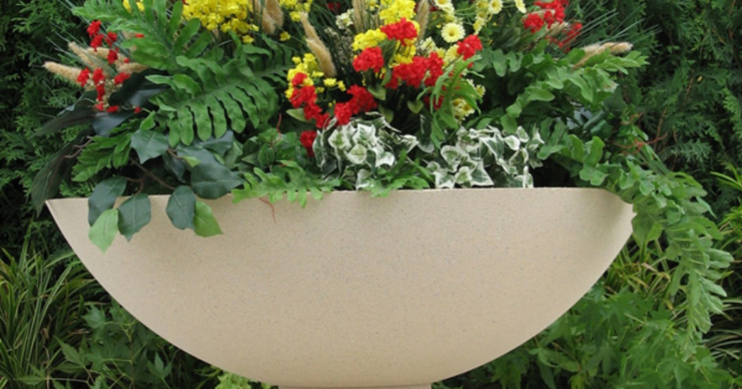 A Frank Lloyd Write Garden Urn, overflowing with beautiful, colorful flowers.