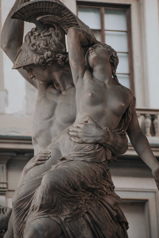 A professional high-definition photo of a man embracing a naked woman, her breasts exposed.