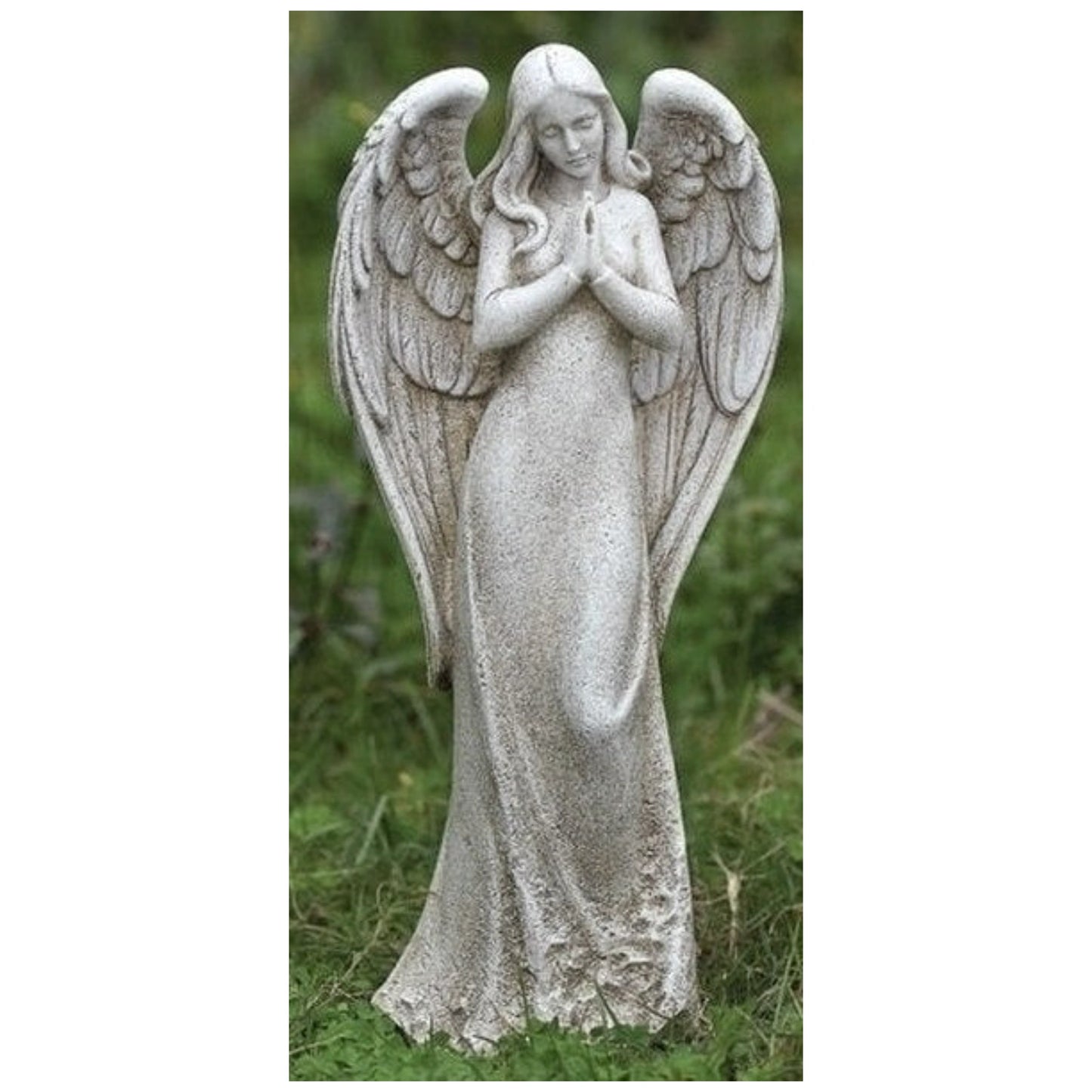 Graceful stone angel statue with hands in prayer, wings spread, standing in a grassy garden.
