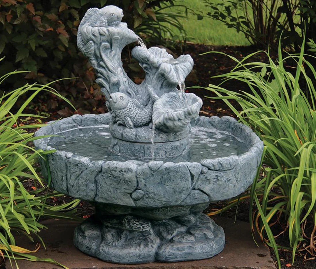 Decorative stone water fountain with fish sculptures in a garden setting
