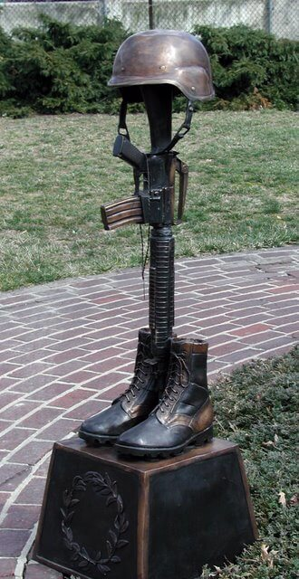 Bronze sculpture of a helmet, boots, and rifle on a pedestal outdoors Battle Cross Boots War Memorial Sculpture Bronze Tribute Statue Large
