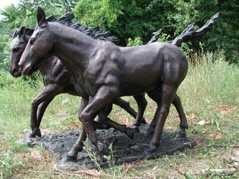 Bronze sculpture of three horses running in a natural setting table base