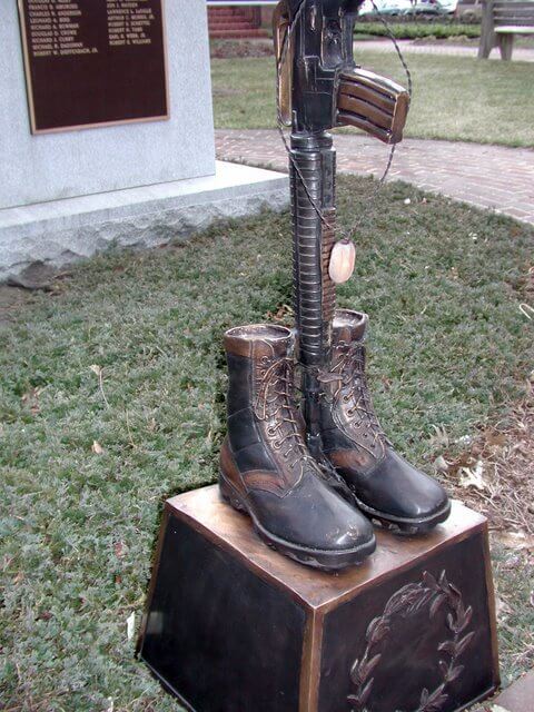 Bronze sculpture of boots and a rifle on a pedestal outdoors Military War Memorial statue high end Tribute