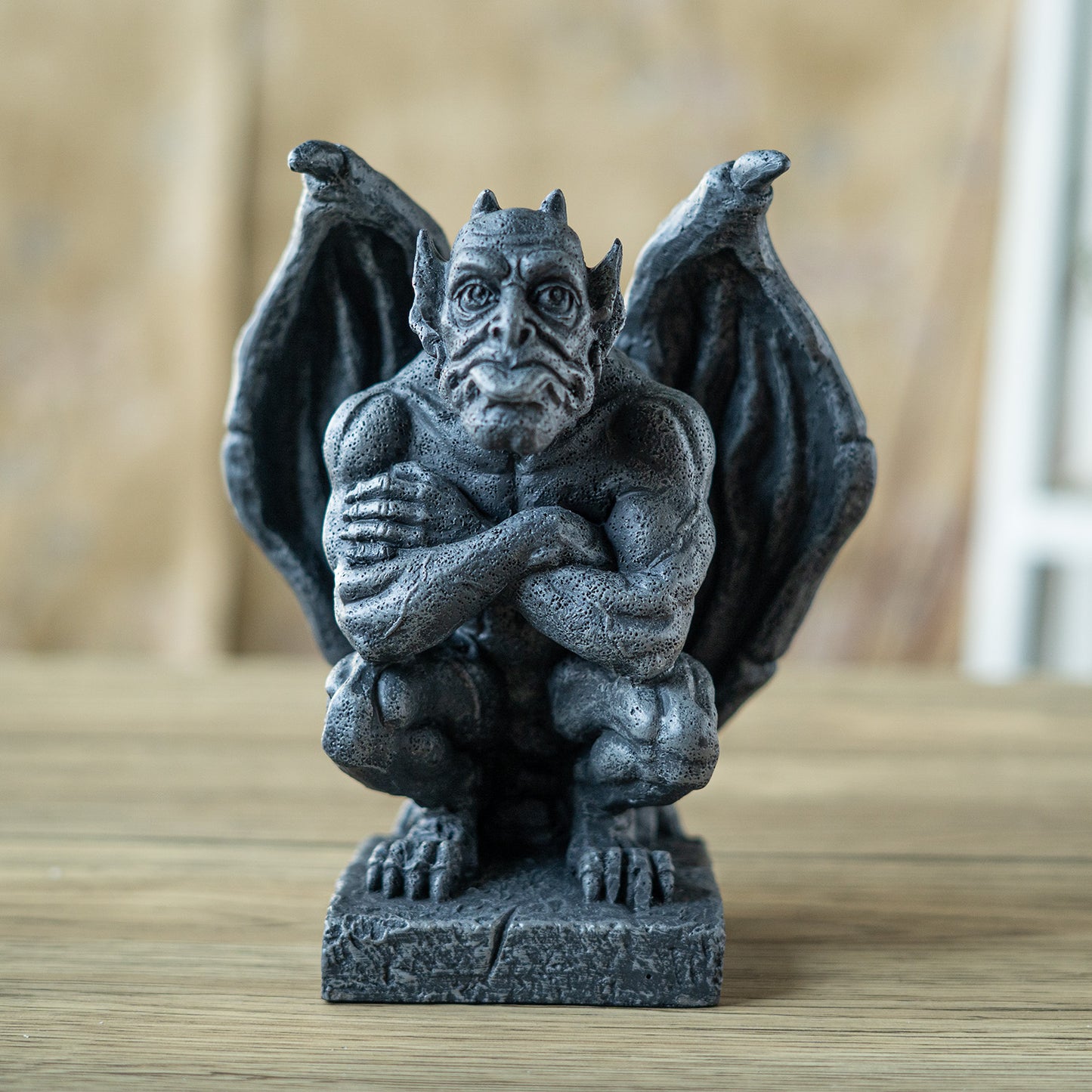 Statue of a gargoyle on a wooden surface with a blurred background
