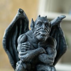 Statue of a gargoyle with wings in a blurred indoor setting close up of face