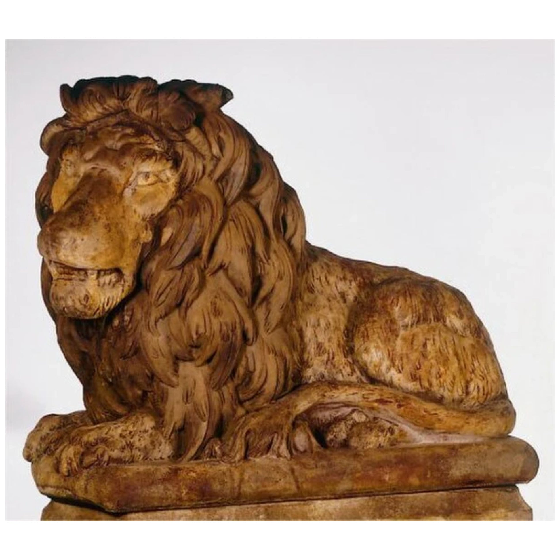 A large, regal cast stone lion sculpture reclining with its head turned to the left, detailed with a textured mane and lifelike expression.