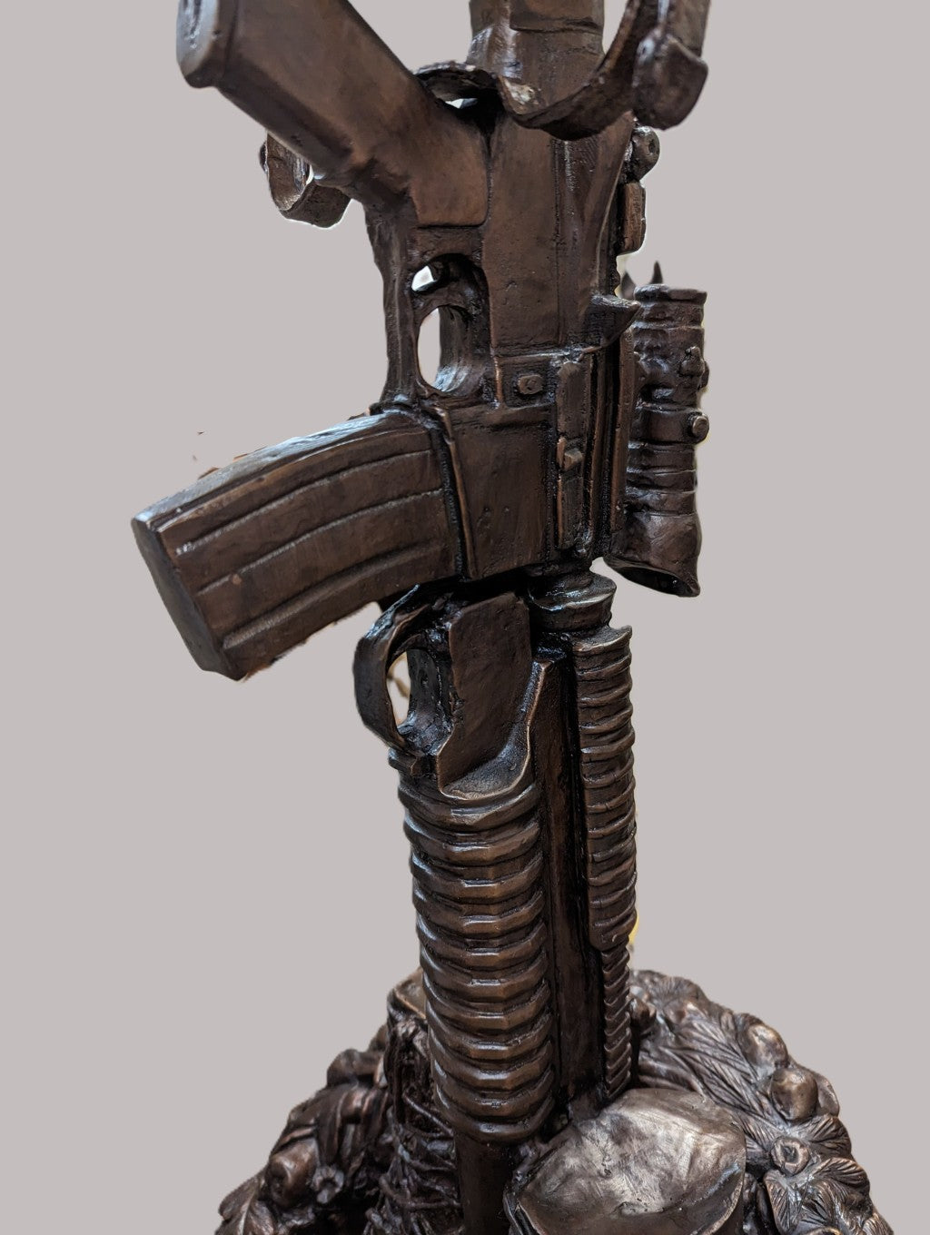 Bronze sculpture of a gun on a gray background battle boots memorial bronze statue