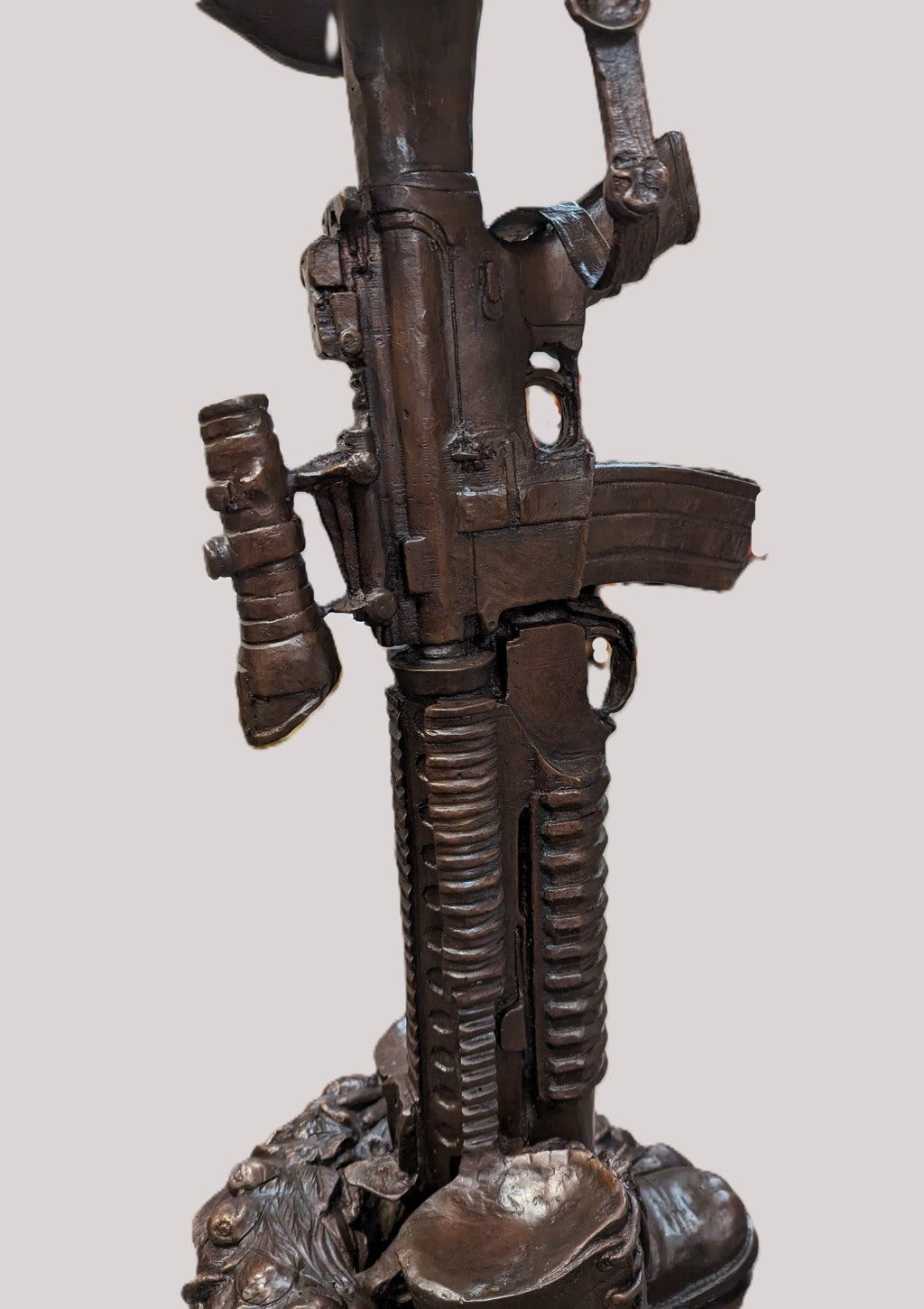 Bronze sculpture of a gun with intricate details on a white background Battle Boots Cross