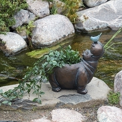 Hippo with bird planter sculpture featuring a whimsical hippo holding greenery with a small bird perched on its nose, displayed beside a garden water feature.