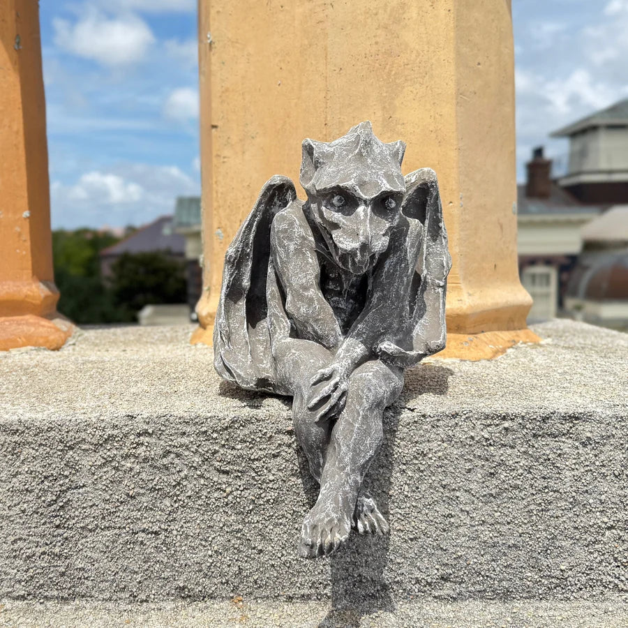 Gargoyle statue on a building with columns in the background
