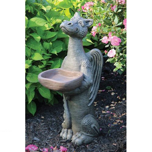 Dragon-shaped bird bath in a garden setting with greenery and flowers.