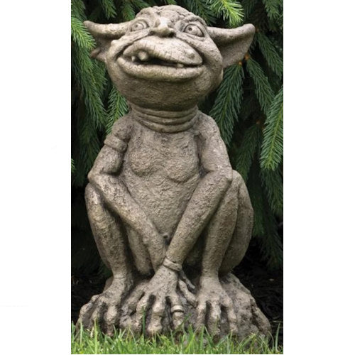 Stone gargoyle statue against a green leafy background