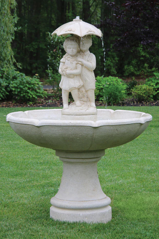 Stone fountain with statues of children holding an umbrella in a garden setting