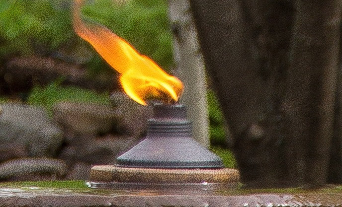 Flaming torch on a fountain top pedestal shows fire when lit with a natural background