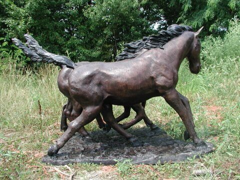 Bronze sculpture of a horse in a natural setting with trees and grass side view of table base