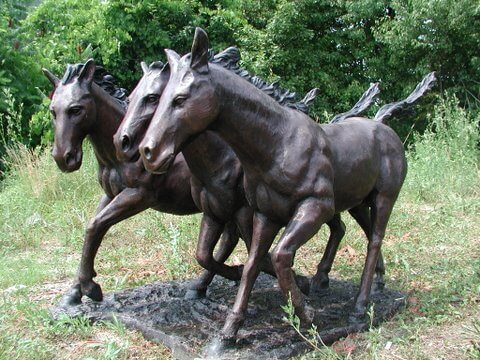 Bronze sculpture of three horses running in a natural setting cocktail table table base
