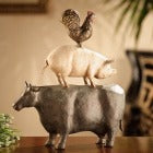 A cow with a pig on its back, the pig has a chicken stand him his back.  The full Barnyard in 1 sculpture