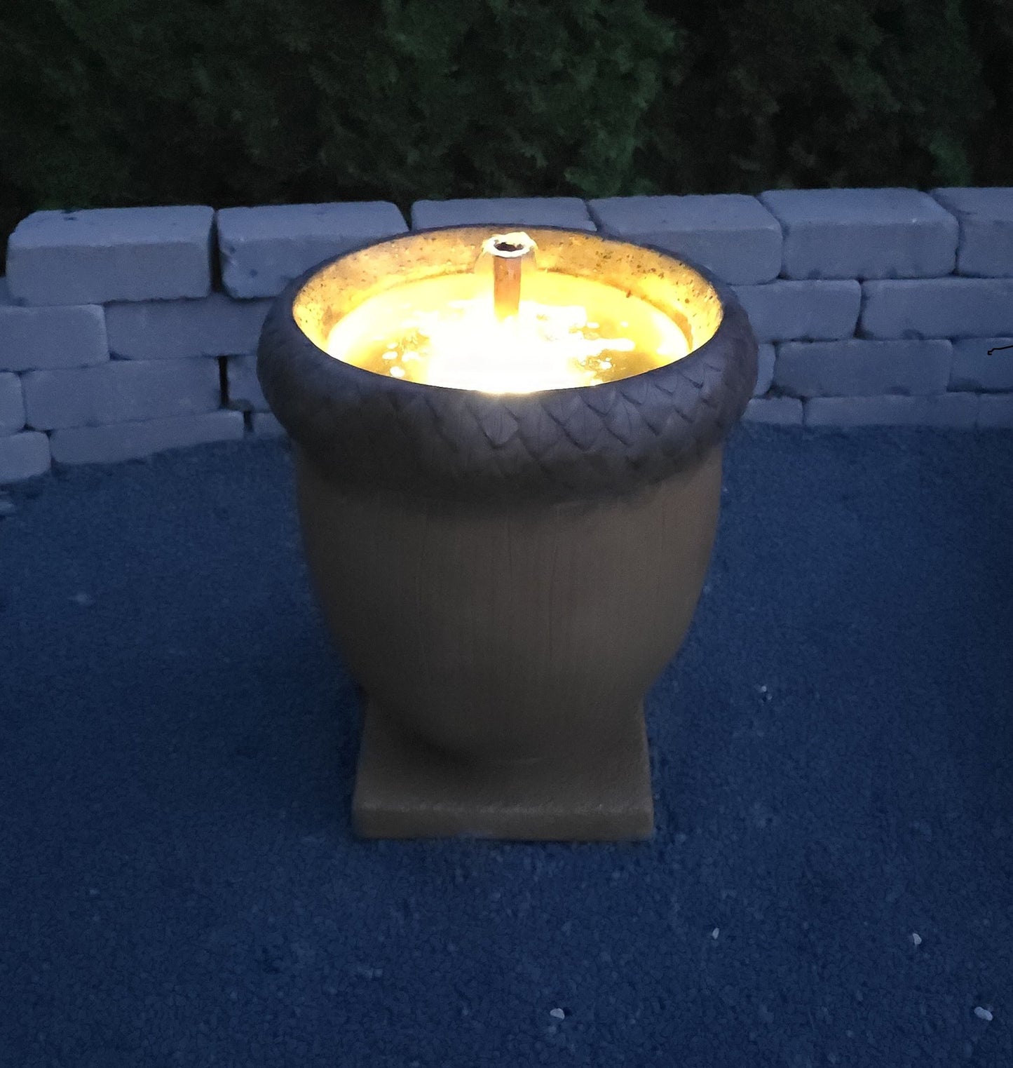 High-end cast stone acorn fountain with bubbling spout and square base nighttime view lighted