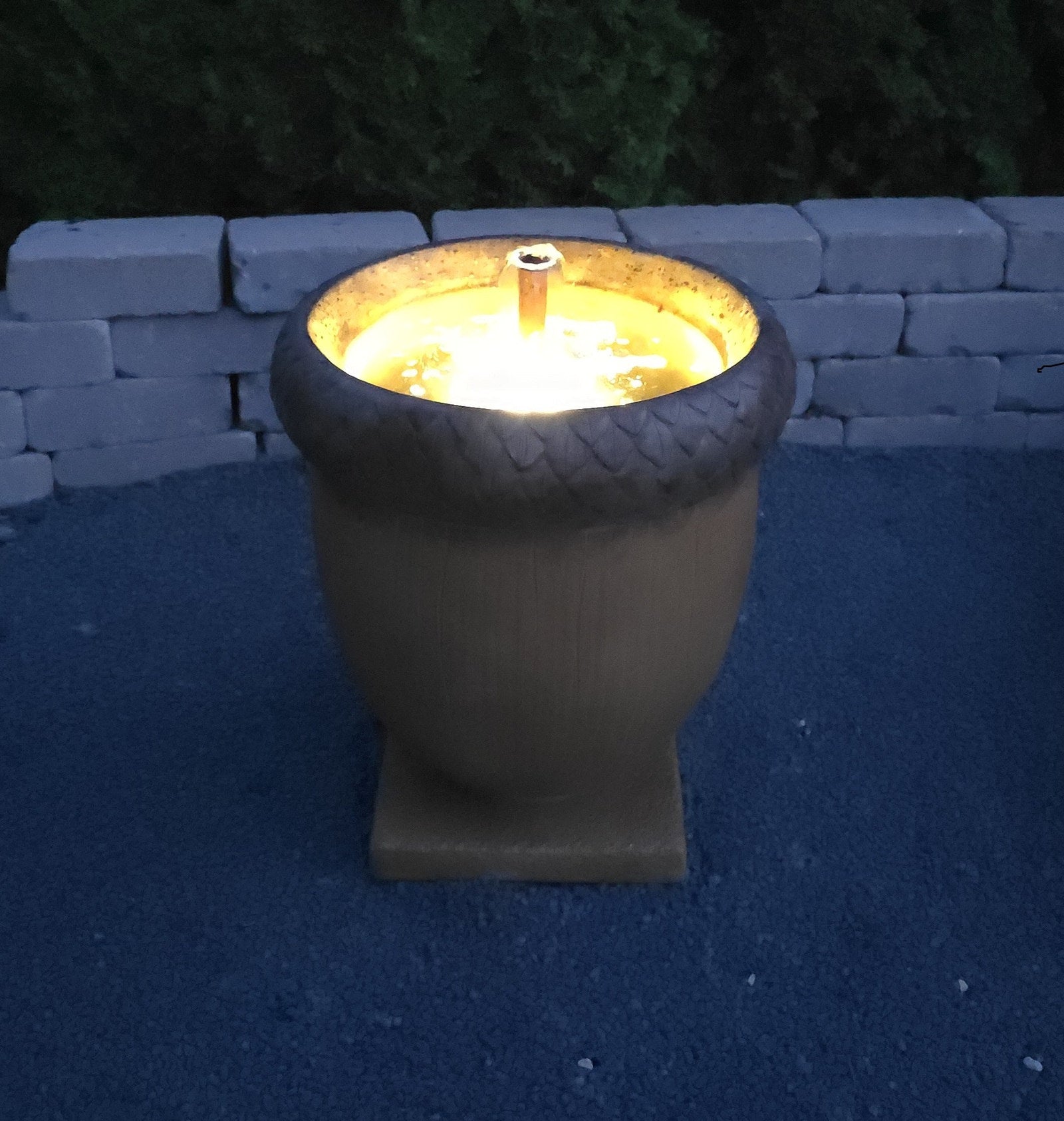 High-end cast stone acorn fountain with bubbling spout and square base nighttime view lighted