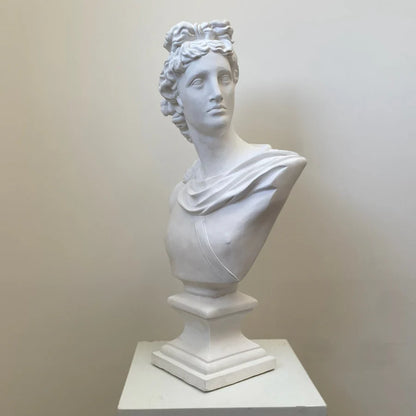 White marble bust of a classical figure on a pedestal against a plain background