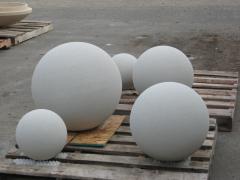 Five large white spherical stone or concrete plant markers of varying sizes displayed on wooden pallets outdoors on a gray concrete surface.
