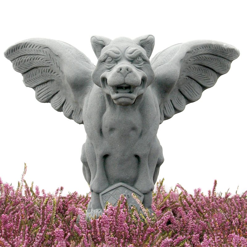 A gray stone gargoyle statue with spread wings, shown above a bed of pink heather flowers against a white background. Architectural colors