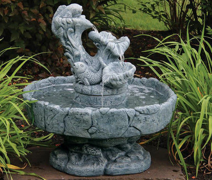 Decorative stone water fountain with fish sculptures in a garden setting