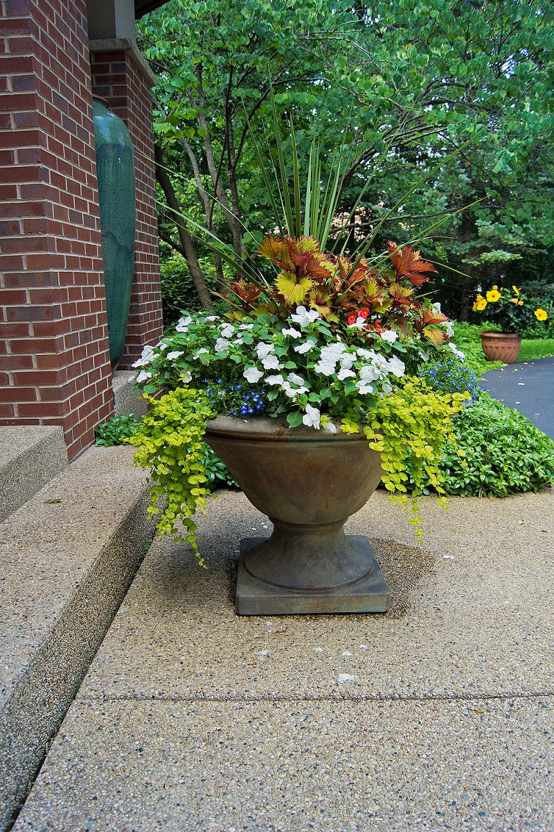 Avanti low estate garden urn cast stone planter shown with flowers in urn