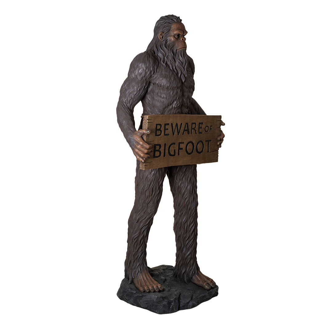 Statue of a Sasquatch holding a 'Beware of Bigfoot' sign on a white background