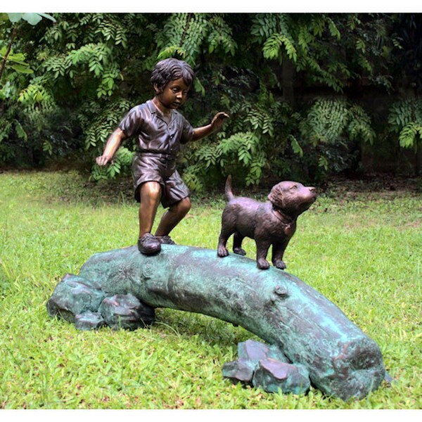 Boy following dog across log bronze garden statue sculpture tree artwork