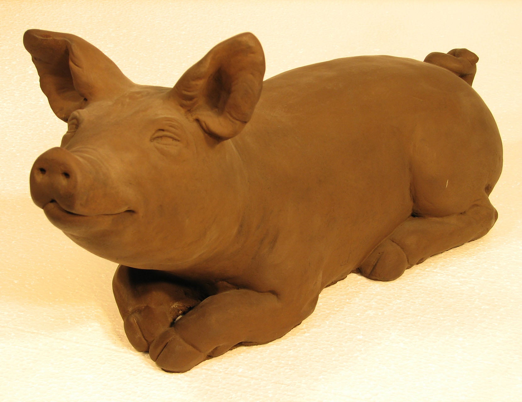 Terracotta pig sculpture on a beige background