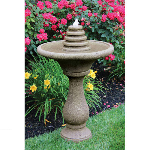 Stone garden fountain with flowers and greenery in the background