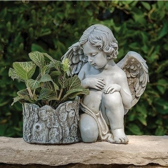 Cherub angel planter statue holding a bark-style pot, sitting peacefully in a garden