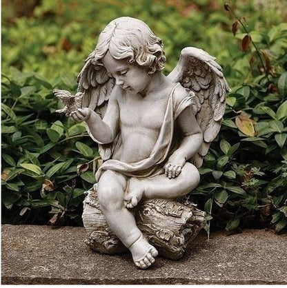 Statue of an angel holding a dove bird in a garden setting sitting on log