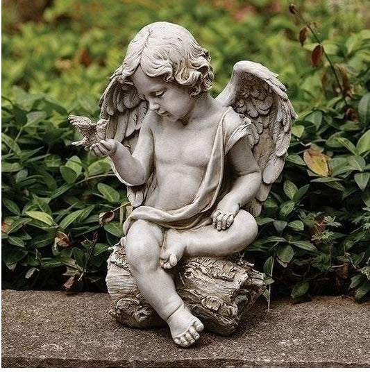 Statue of an angel holding a dove bird in a garden setting sitting on log