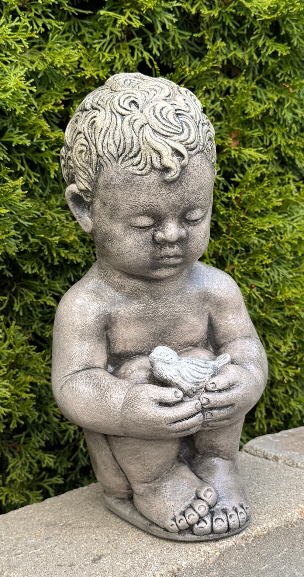 Child Holding Bird garden statue captures a tender moment frozen in time