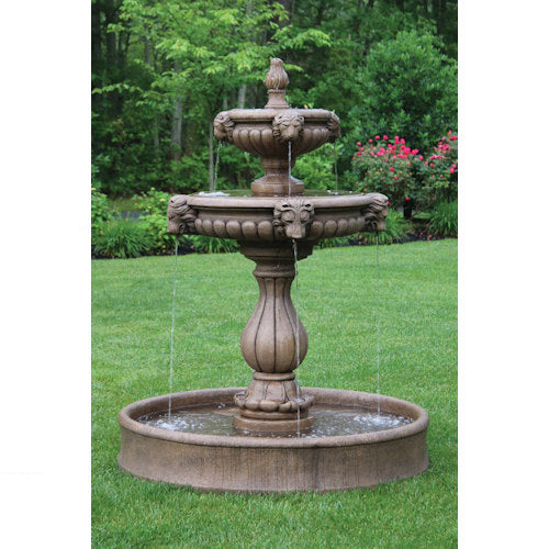 Three-tiered stone fountain in a garden setting with green grass and trees.
