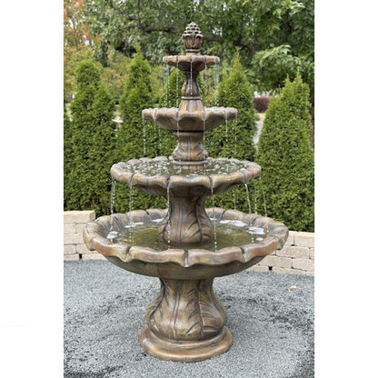 Three-tiered stone fountain with water flowing in a garden setting with pineapple finial top spouting