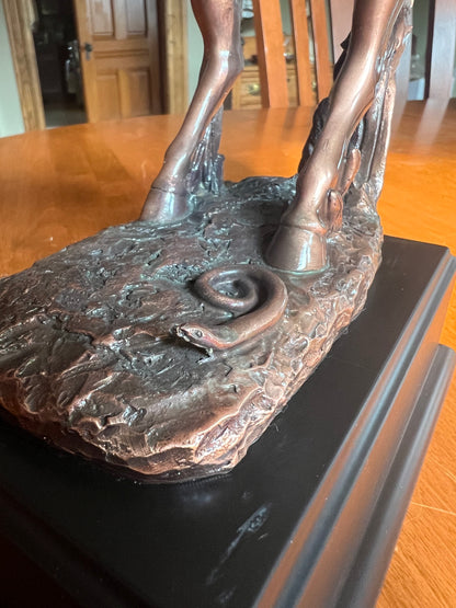 Close up of snake at base of statue Rodeo cowboy sculpture with startled horse and snake detail