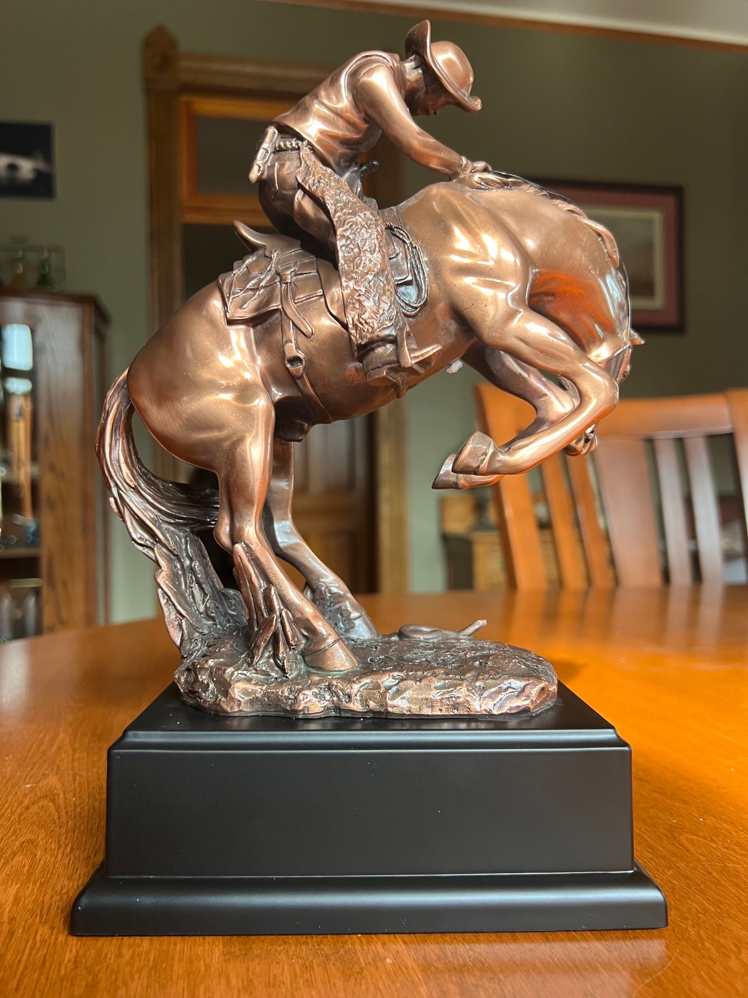 Back view of statue Cowboy struggling to control a bucking stallion sculpture