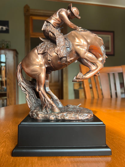 Back view of statue Cowboy struggling to control a bucking stallion sculpture