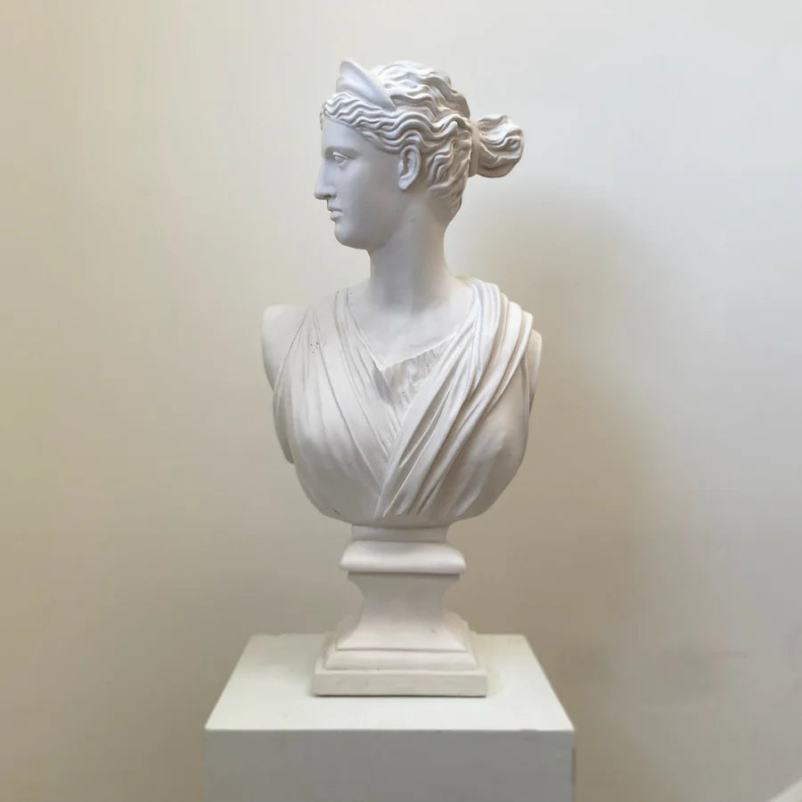 White marble bust of a classical woman on a white pedestal against a plain background