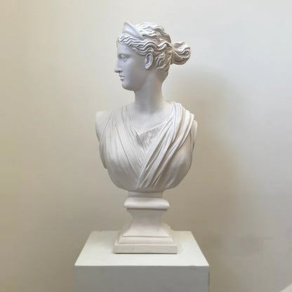 White marble bust of a classical woman on a white pedestal against a plain background