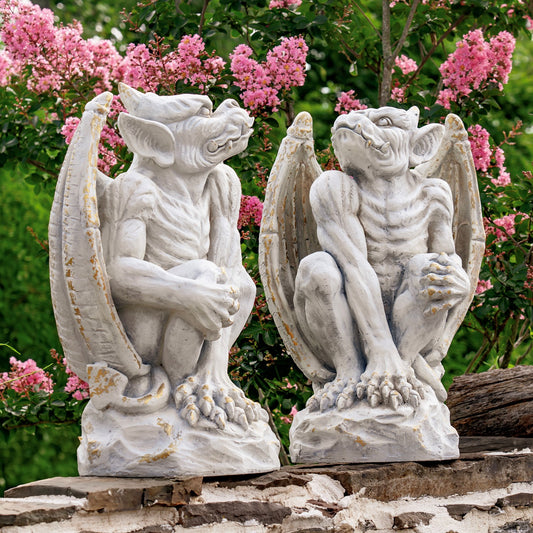 Two stone gargoyle statues in front of pink flowering trees