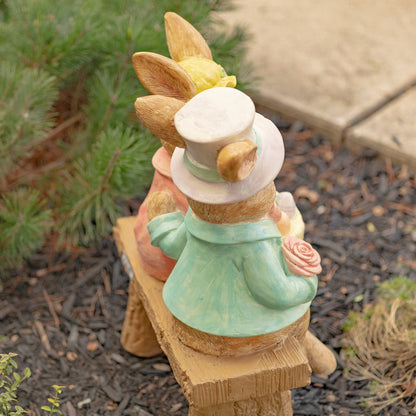 Back view Hand-painted bunny couple sitting on a bench holding a basket of Easter eggs