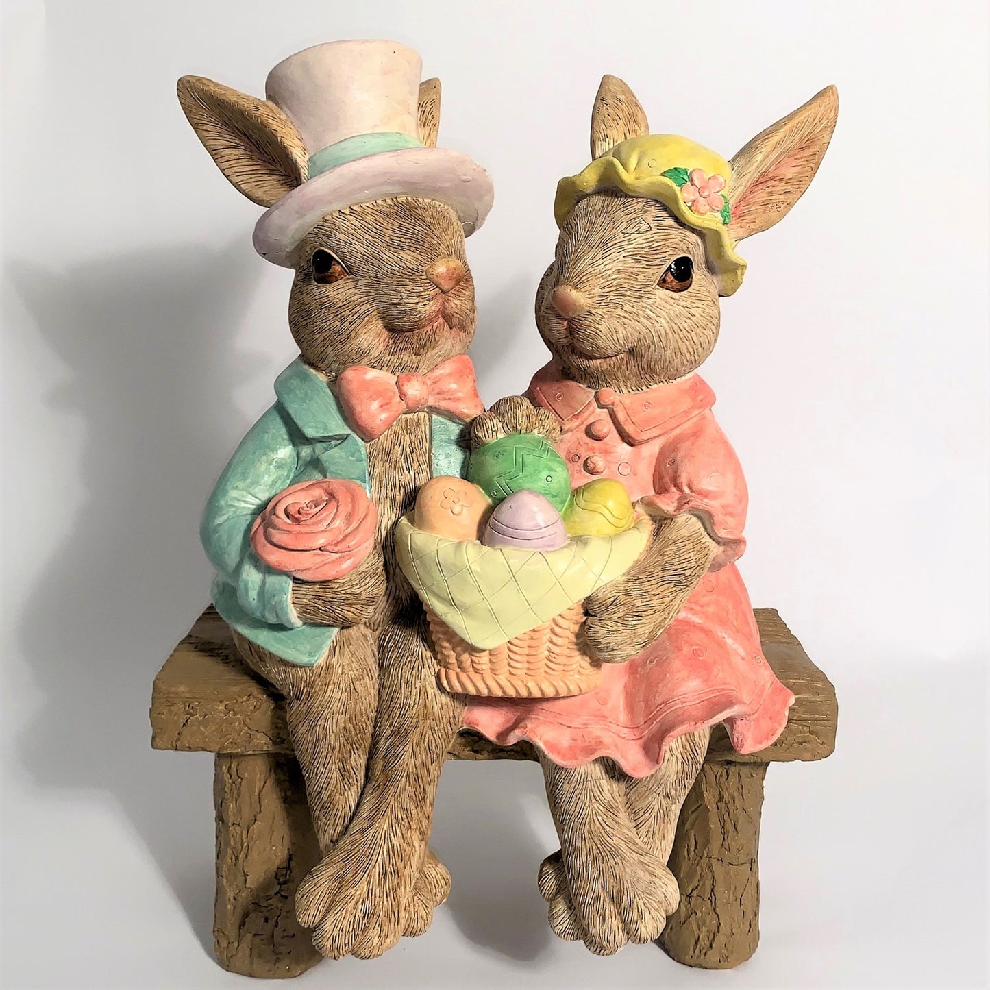 Two decorative rabbit statues with Easter eggs on a white background