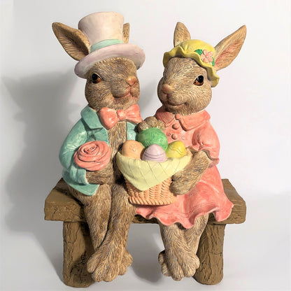Two decorative rabbit statues with Easter eggs on a white background
