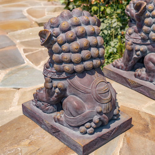 Asian Stone lion sculpture back view on a stone surface with greenery in the background