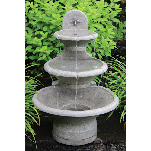 Three-tiered stone fountain with water flowing in a garden setting
