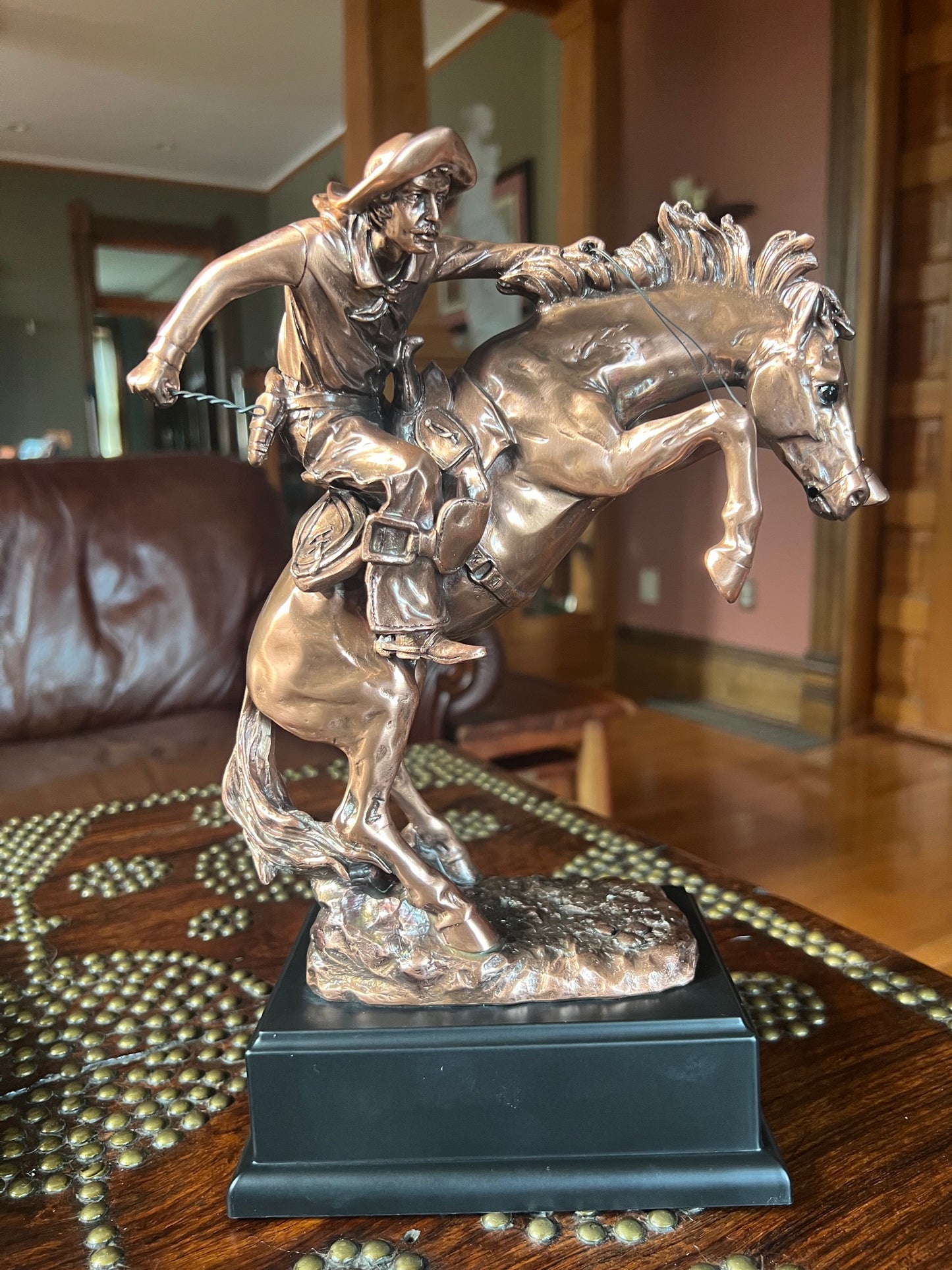 Frontier cowboy struggling to control a rearing horse statue